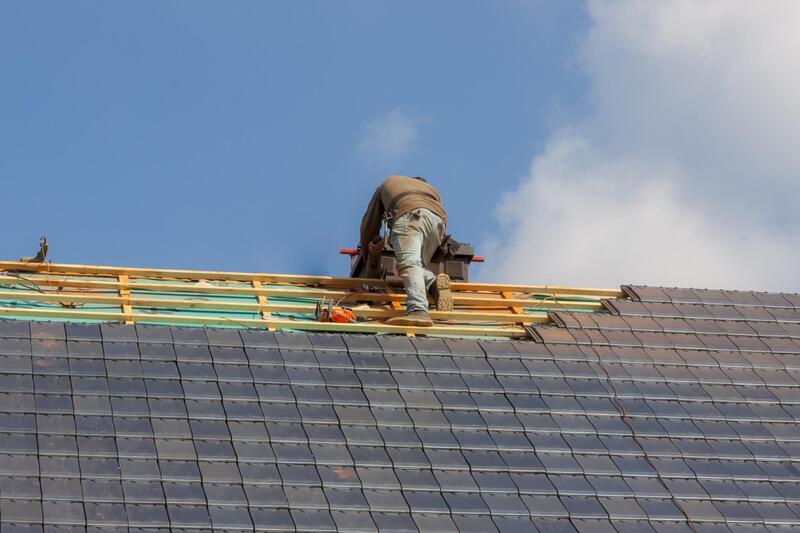 Man working on the last part of installing shingles onto a new roof working For Delaware County Roofers